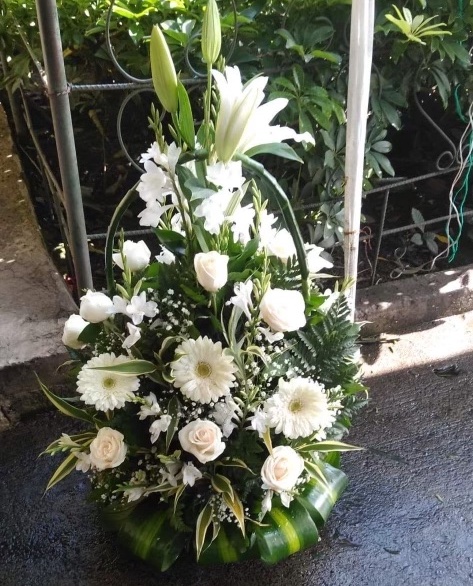 An image of white roses, daisies, and lilies in a basket arrangement