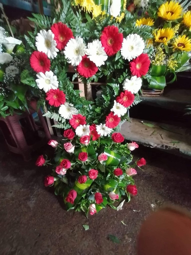 An image of pink roses made into an arrangement with a heart made out of red and white daisies