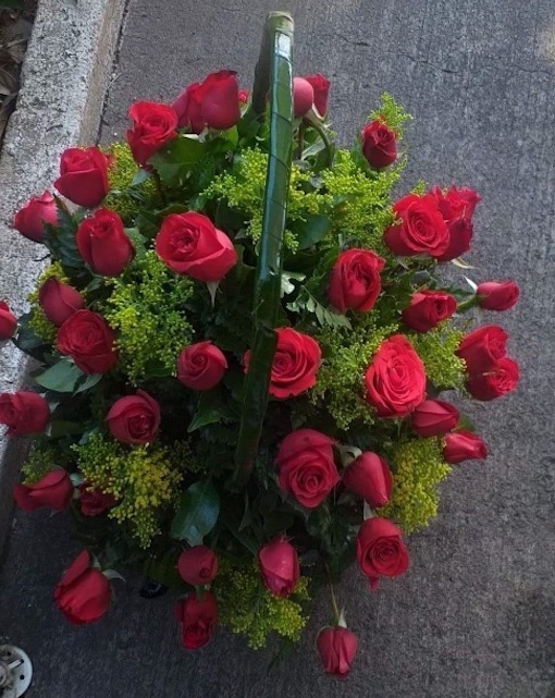 An image of red roses with greenery in a basket