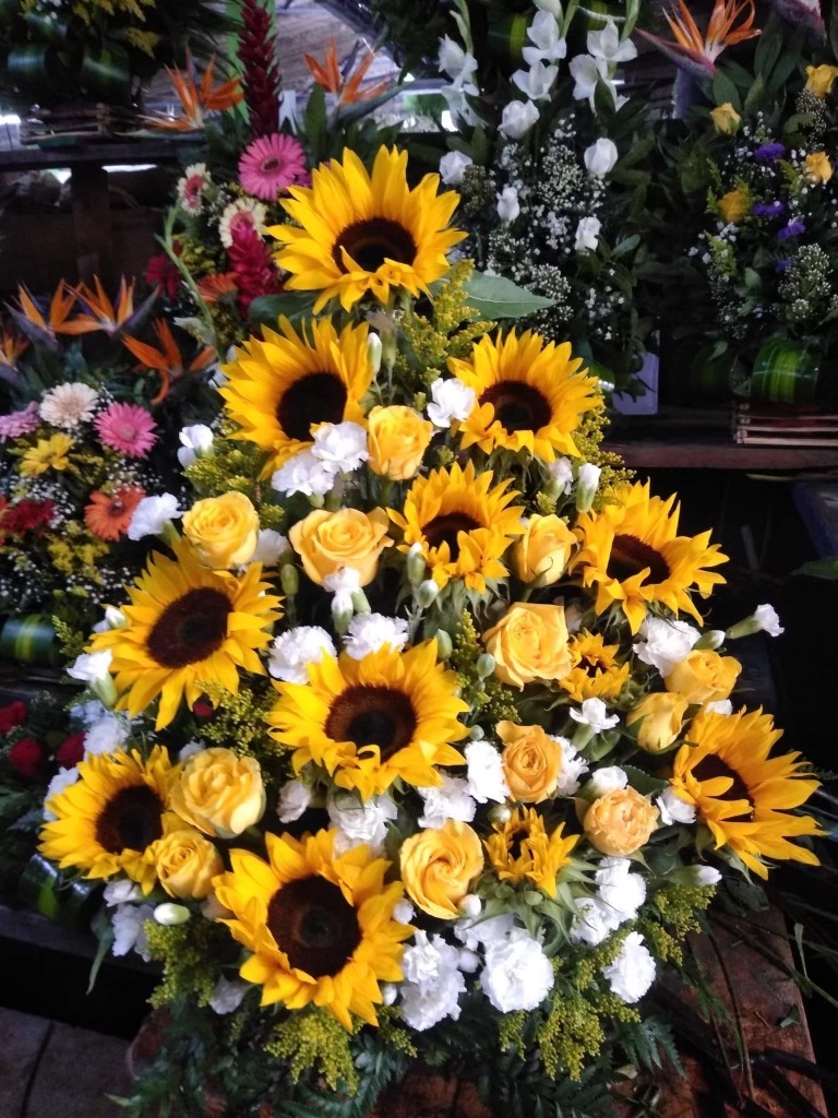 An image of yellow sunflowers with yellow and white roses in an arrangement